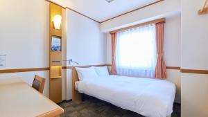 东京Toyoko Inn Tokyo Nihombashi Hamacho Meijiza Mae的小房间设有床和窗户