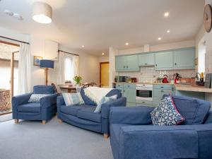 Clyst Saint MaryThe Stables的一间带2张蓝色沙发的客厅和一间厨房