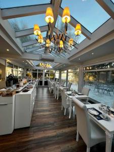 奥斯赛拜-塞林Strandhotel Lindequist的餐厅配有白色的桌椅和吊灯