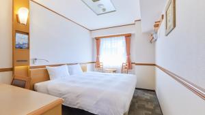 东京Toyoko Inn Tokyo Nihombashi Zeimusho Mae的小房间设有白色的床和一张桌子