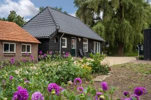 阿纳姆Vakantiehuisje aan de rand van Arnhem的一座带紫色花卉花园的房屋