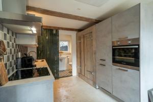 阿纳姆Vakantiehuisje aan de rand van Arnhem的厨房配有不锈钢用具和木柜