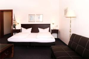 肯普滕福尔斯坦恩霍夫酒店的一间卧室配有一张大床和一张沙发