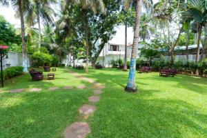 马哈巴利普拉姆Shelter Beach Resort的庭院里种有长椅和棕榈树的公园