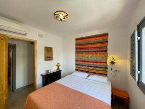 萨各夫雷纳Las Tres Hermanas的卧室配有一张床铺,墙上挂着五颜六色的毯子
