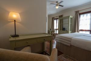 拉拉古纳拉古纳尼瓦利亚Spa大酒店的一间卧室配有一张床和一张带台灯的书桌