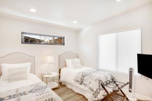 斯廷博特斯普林斯Sunlight Retreat的一间白色卧室,配有两张床和电视