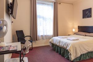 格洛斯特City Centre Guest House的配有一张床、一张书桌和一扇窗户的酒店客房