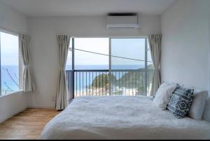 下田Sirahama Beach House的一间卧室设有一张床,享有海景