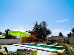 本苏莱曼Ferme Sacrée Nature的一个带绿色遮阳伞和椅子的游泳池