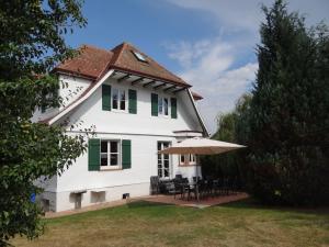 Gemeinde AichhaldenSchwarzwaldhaus24 - Ferienhaus mit Sauna, Whirlpool und Kamin的白色的房子,配有桌子和雨伞