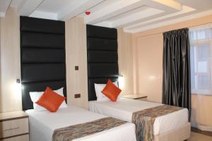 内罗毕机场着陆酒店的两张床铺,配有黑色和橙色枕头