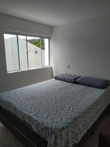 皮涅拉Loft/APTO em Praia da Pinheira的白色客房的一张床铺,设有大窗户
