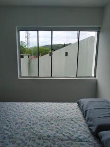 皮涅拉Loft/APTO em Praia da Pinheira的一间卧室设有一张床和一个大窗户