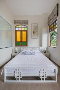 普吉镇O'nya Phuket Hotel - SHA Extra Plus的白色卧室设有一张大床和两个窗户
