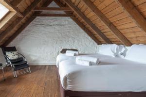 凯里肯Isle of Skye Cottage的阁楼卧室配有两张床和椅子