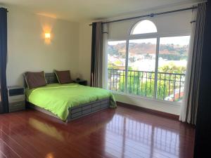 塔那那利佛Appartements - Le Paradisier Ambatobe的一间卧室设有一张绿色的床和一个大窗户