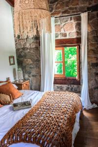 塔菲德尔瓦勒Castillo de Piedra Tafi del Valle的一间卧室设有一张带石墙的大床