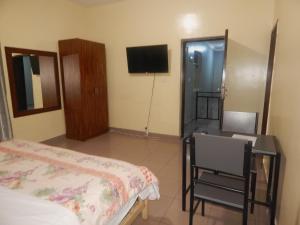 基加利SERENITAS Apartment的一间卧室配有一张床、一张书桌和一台电视