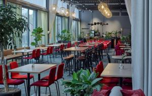 阿兰达Scandic Arlandastad的一间设有桌子和红色椅子的餐厅,种植了植物
