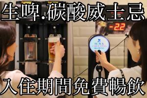 那霸Okinawa Hinode Resort and Hot Spring Hotel的坐在机器前拿着一杯啤酒的女人