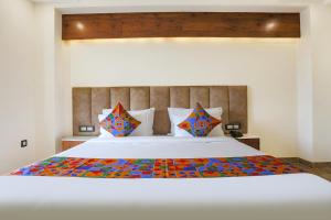 古尔冈FabHotel Golf Inn Golf Course Road Gurgaon的卧室配有一张带彩色枕头的大型白色床。