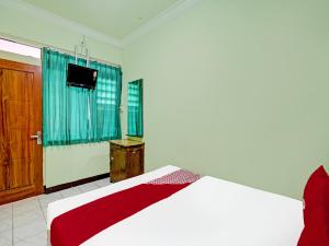 RamekasanOYO 2708 Hotel Kemuning Syariah的一间卧室配有一张床和一台电视