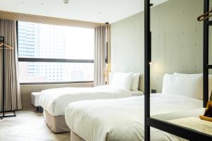 高雄高雄行旅的酒店客房设有三张床和窗户。