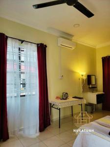 马六甲NusaTuah Roomstay的客房设有一张床和一张桌子,并带有窗户