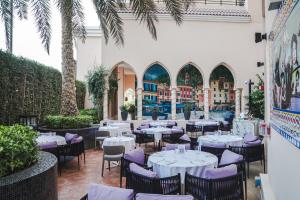 多哈Al Gassar Resort的餐厅拥有白色的桌椅和棕榈树
