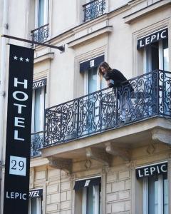 巴黎29乐匹克酒店的建筑物阳台上的妇女