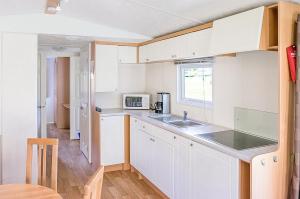 GamlebyKustCamp Gamleby的厨房配有白色橱柜、水槽和窗户。
