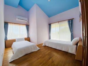 恒春古城垦丁卡米克特色民宿的配有蓝色天花板和木地板的客房中的两张床