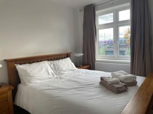 WansteadFamily friendly new flat at London Gants Hill Station near Ilford的一间卧室配有带2条毛巾的床和窗户。
