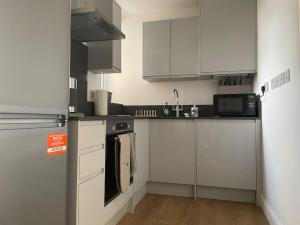 WansteadFamily friendly new flat at London Gants Hill Station near Ilford的小厨房配有白色橱柜和微波炉