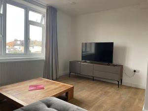 WansteadFamily friendly new flat at London Gants Hill Station near Ilford的客厅配有平面电视和桌子。