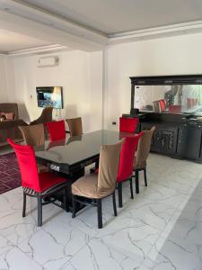 亚历山大Vilaria King mariot fully air conditioned villa فيلاريا كنج مريوط فيلا مكيفه بالكامل的一间设有玻璃桌和红色椅子的用餐室