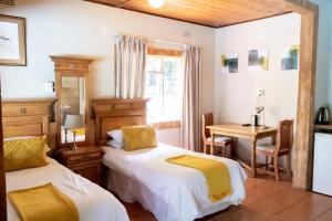 帕拉博鲁瓦太阳鸟旅舍的客房设有两张床、一张桌子和一张书桌。