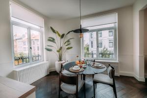 安特卫普Sud d'Anvers的一间带桌椅和2扇窗户的用餐室