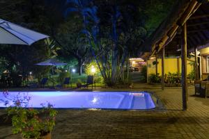 帕拉博鲁瓦太阳鸟旅舍的夜间游泳池,带遮阳伞