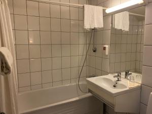 沃斯沃斯凡根公园酒店的白色瓷砖浴室设有水槽和浴缸