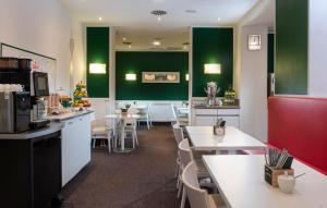 杜塞尔多夫杜塞尔多夫市中心温德姆花园国王大道酒店的餐厅设有白色的桌子和绿色的墙壁