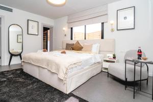 特拉维夫New Duplex 3 Bedroom with Jacuzzi的白色卧室配有一张大床和椅子