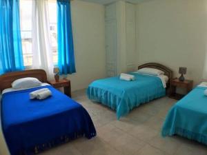 阿约拉港El Paraiso的一间卧室配有两张带蓝色床单和蓝色窗帘的床