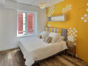 圣让-德吕兹RESIDENCE HARCOURT SAINT-JEAN-DE-LUZ的一间卧室设有一张床和黄色的墙壁
