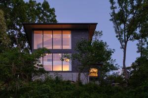 伊东Playliving IZU - A ocean view villa with Onsen的窗户上闪烁着太阳的房子