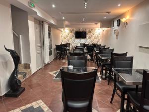 巴黎阿维农酒店的餐厅设有黑色桌椅和电视。