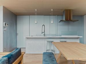 伊东Playliving IZU - A ocean view villa with Onsen的厨房配有木桌和蓝色沙发。