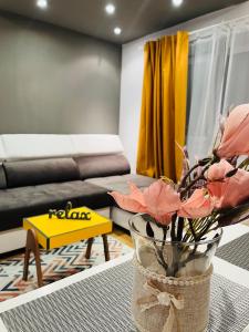 雅西Confort View Apartment Iași - 3 rooms-Like Home的客厅配有沙发和鲜花花瓶