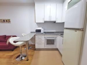 维戈Castrelos, Vigo, diseño的白色的厨房配有桌子和冰箱